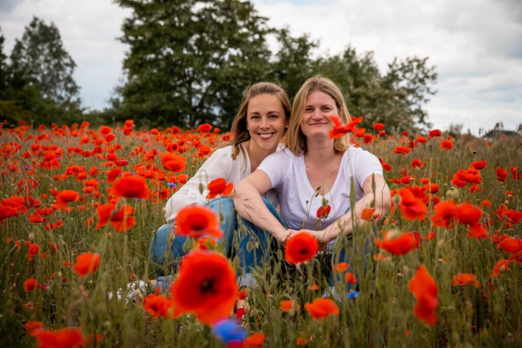 Kristin und Franziska von KristKind sitzen in einem Mohnblumenfeld